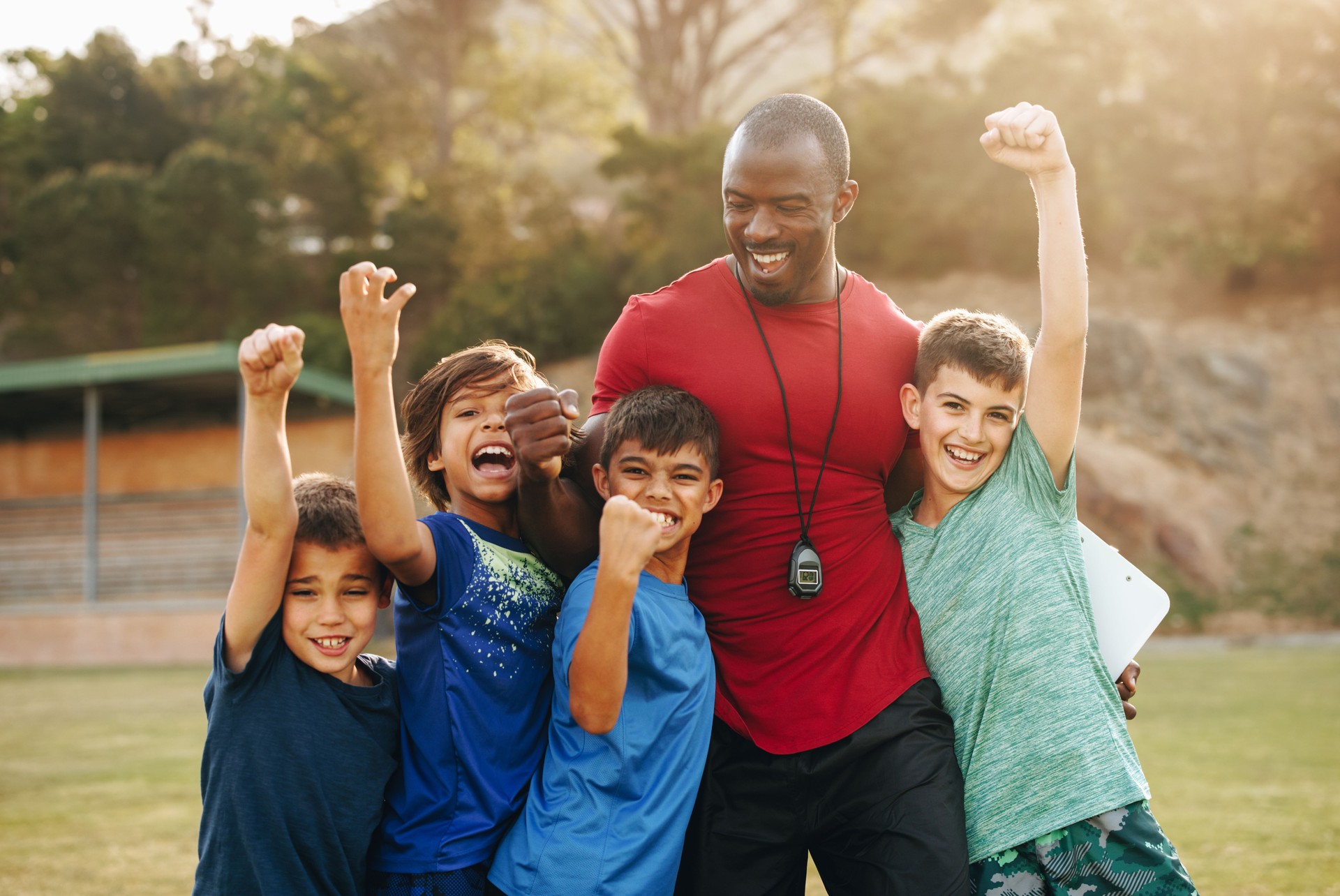 School kids celebrating with their coach on a sports field